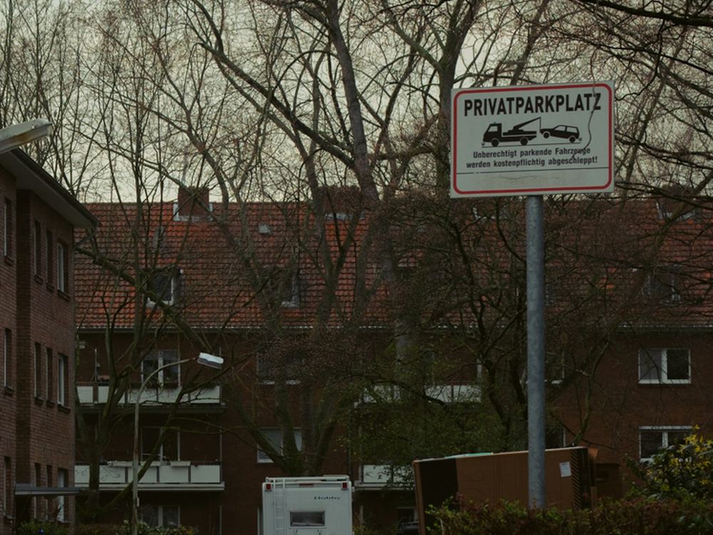 Privatparkplatz-Schild mit Abschlepphinweis vor einer Wohnanlage